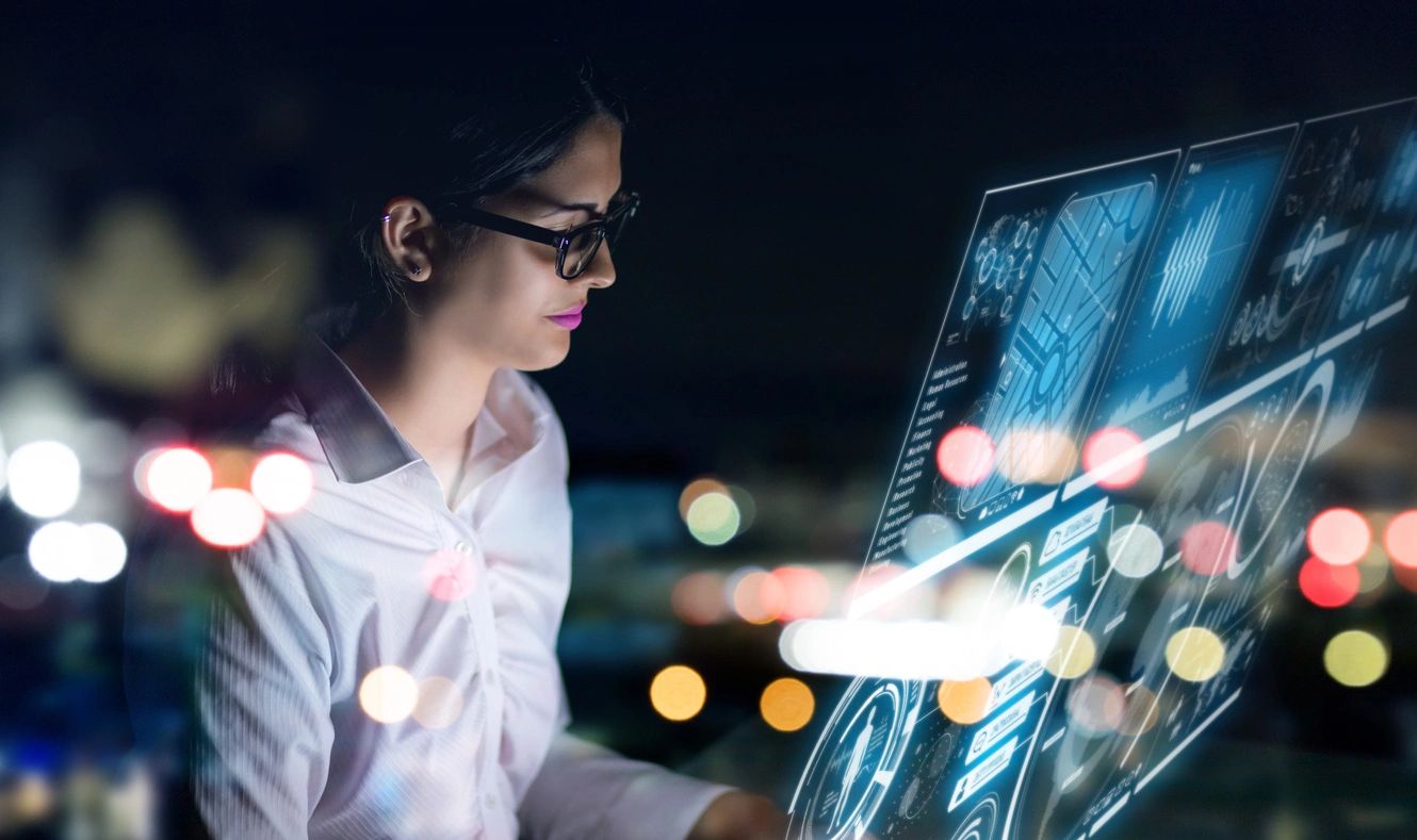 A woman in glasses is looking at the screen of her laptop.