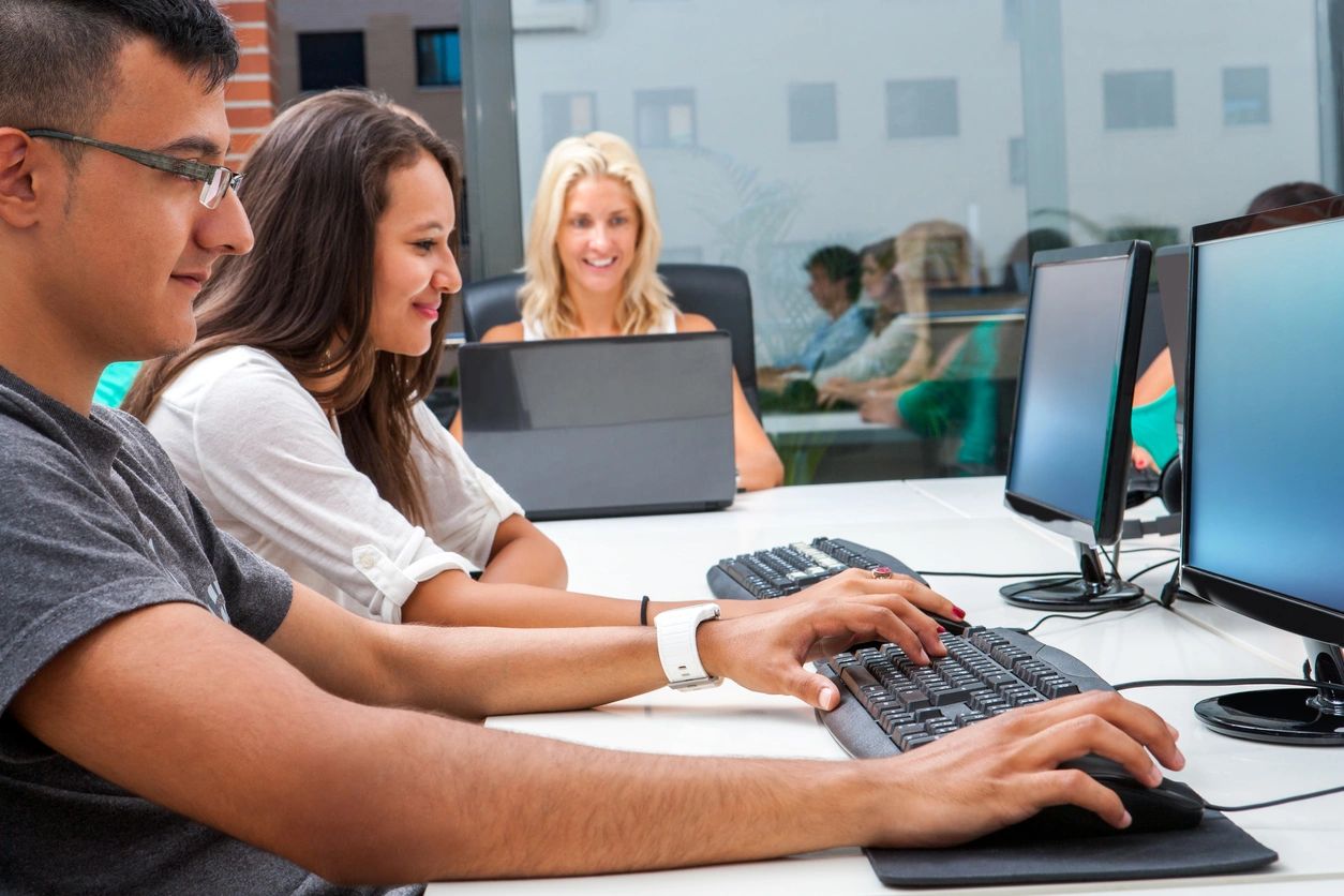 A group of people sitting at a table with computers.